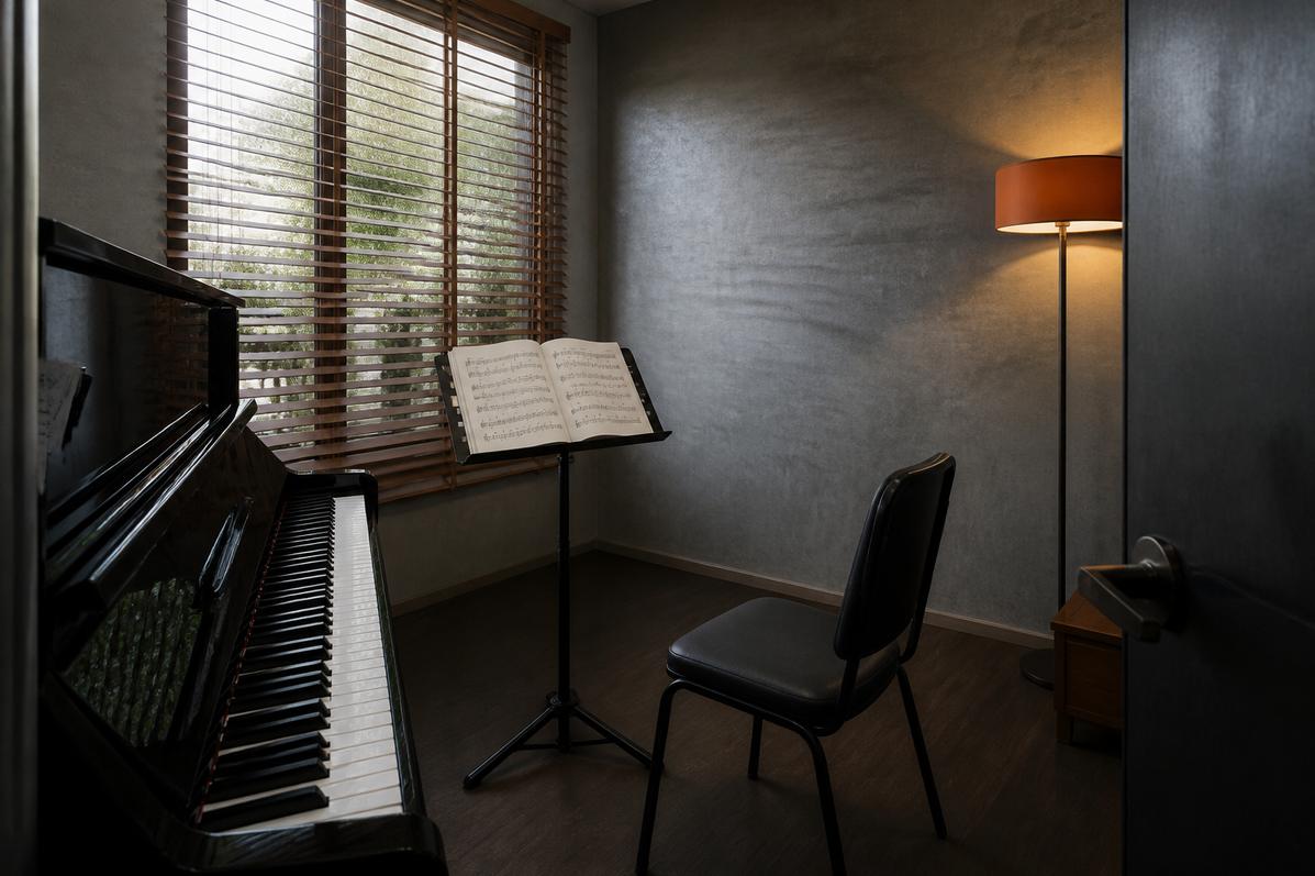 Quiet upright piano room with music stand and warm lamp
